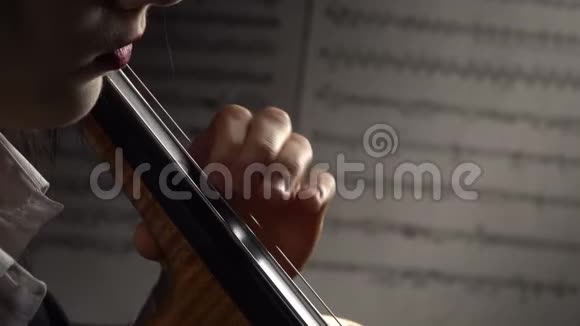 双手放在背景纸中的大提琴弦上并附上音符快关门侧视图视频的预览图