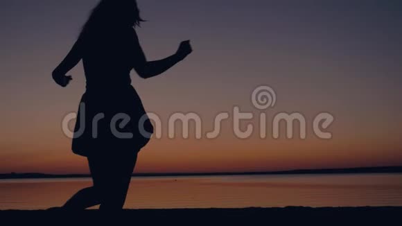 快乐的女人向夕阳跑去海滩举起手臂旋转着视频的预览图