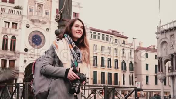 快乐兴奋的女记者带着相机走在秋天的圣马可广场和成群的鸽子在威尼斯慢动作视频的预览图