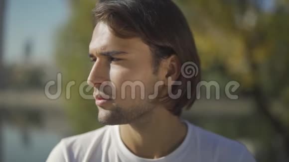 帅哥看着站在公园里的摄像机年轻人特写的脸视频的预览图