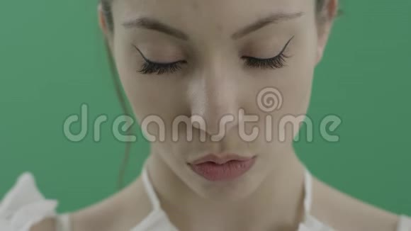 年轻漂亮的女人穿着衣服咬着嘴唇在绿色的背景下有着令人向往的视力视频的预览图