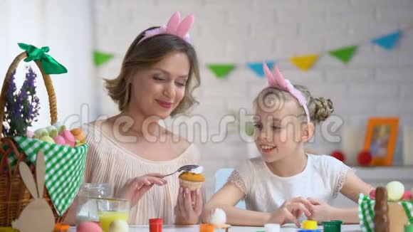 母亲和女儿在家做的蛋糕上加了糖霜并用糖霜装饰它们视频的预览图