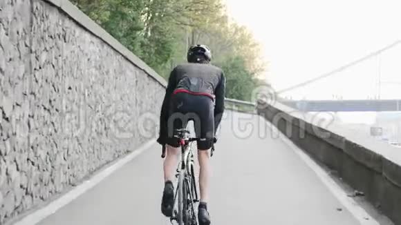 强壮的专业自行车手瘦腿强壮的肌肉骑着上坡的马鞍后面跟着射击自行车训练视频的预览图