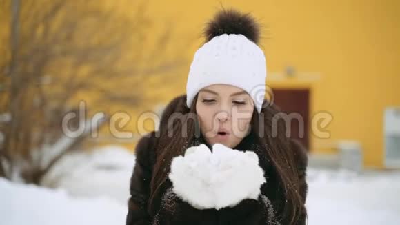 一个穿貂皮大衣的女孩用手套吹雪视频的预览图