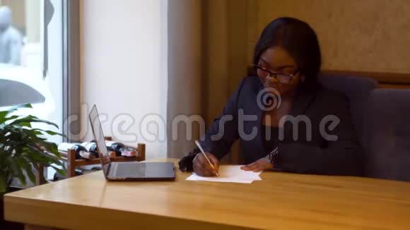 非裔美国女商人用手提电脑和文件工作忙碌的女人在网上银行理财视频的预览图