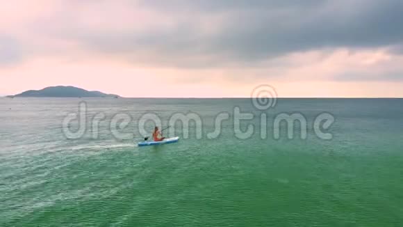 日出时女士坐在平静的海洋中的船上游泳视频的预览图