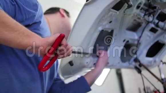 无漆凹痕修补一位男主人正在修理汽车引擎盖上的凹痕没有用优质的钩针作画视频的预览图