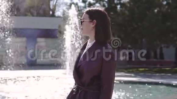 穿着勃艮第夹克礼服的奢华美女走在喷泉附近视频的预览图