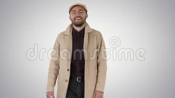 穿着外套的微笑男人看着摄像机在渐变的背景上行走视频的预览图
