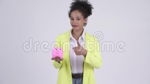 快乐年轻美丽的非洲女商人拿着储蓄罐竖起大拇指视频的预览图