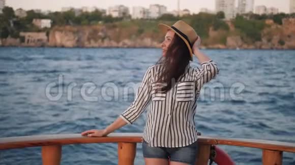 女游客戴着帽子在旧游艇甲板上放松观看慢动作的绿松石水视频的预览图