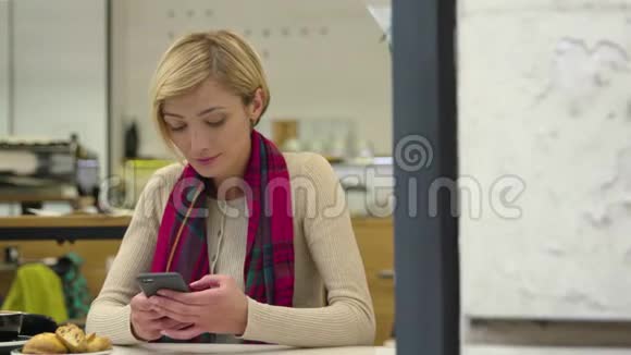 坐在咖啡屋里等待手机的女人视频的预览图