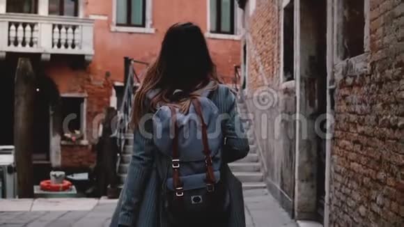 镜头跟随美丽的旅行博主女士在威尼斯街的楼梯上拿着相机散步慢镜头拍照视频的预览图