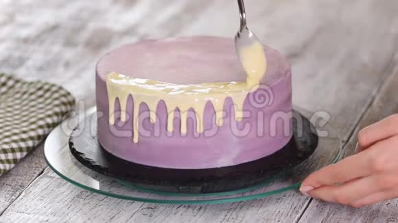 女人用液态白巧克力装饰紫色蛋糕视频的预览图