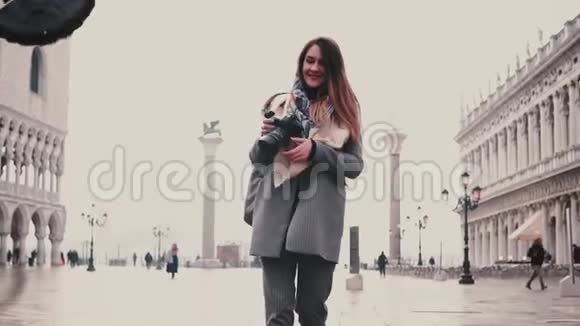 快乐女摄影师带着相机在威尼斯圣马可广场上拍摄鸽子群的照片微笑着慢动作视频的预览图