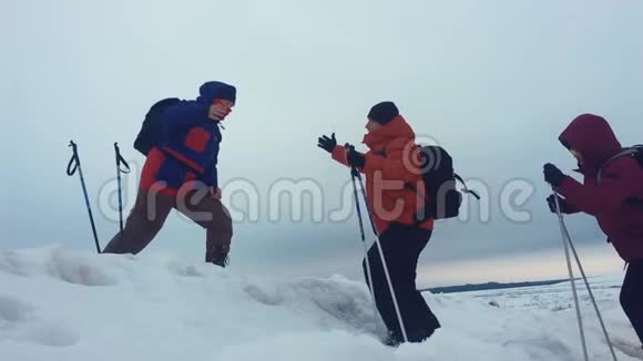 攀爬帮助队友攀爬拿着背包的人伸出一只帮助他的朋友的手三个登山者视频的预览图