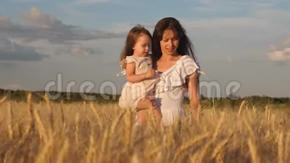 母亲带着婴儿在田里散步手里拿着小麦的小穗妈妈和小女儿走在田野上视频的预览图