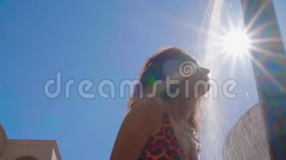 在美丽的蓝天背景和阳光下女士有一个室外沙滩淋浴配有淡水动作缓慢视频的预览图