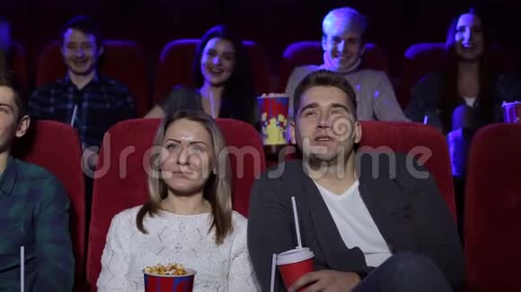 积极的夫妇在电影院喝可乐和吃爆米花视频的预览图