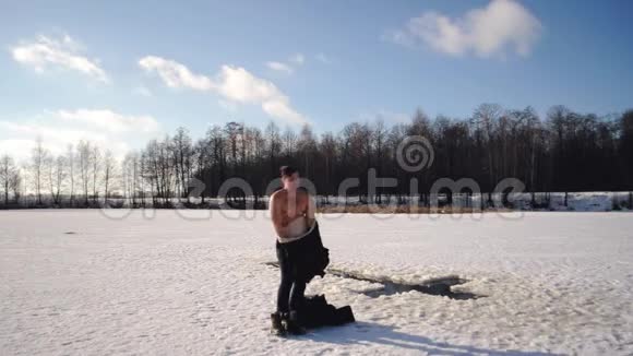 一个穿着黑色夹克的人来到冰冻的湖中游泳这是俄罗斯传统的哈里发泡沫视频的预览图