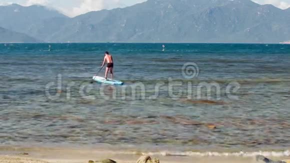 盖伊在海边靠山的沙滩上冲浪视频的预览图
