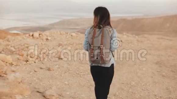 带背包的女人在多云的沙漠里散步年轻体贴的高加索女孩在干沙上徘徊微笑着以色列4K视频的预览图