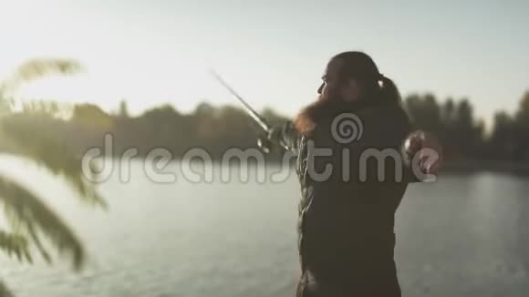 渔夫把鱼竿扔进河里大胡子的渔夫拿着鱼竿站在河岸边钓鱼视频的预览图