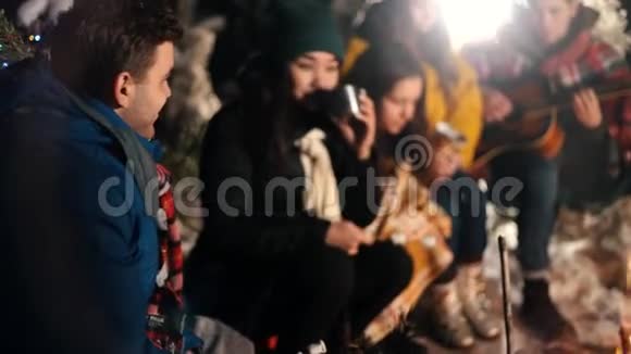 一群快乐的朋友坐在冬天的森林里吃着棉花糖一个年轻的女人在调情视频的预览图