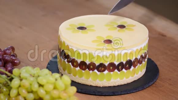 用刀子切慕斯蛋糕和葡萄用葡萄装饰的圆慕斯蛋糕视频的预览图
