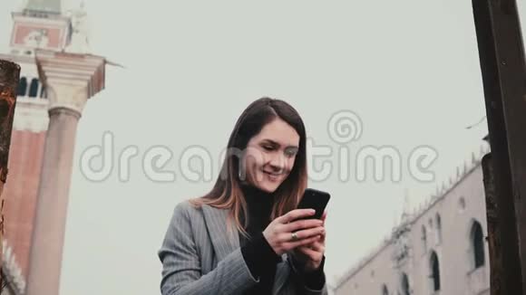 快乐迷人的白种人女游客在意大利威尼斯老城的古建筑上拍照视频的预览图