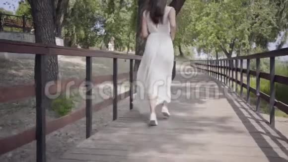 肖像可爱的年轻女孩黑发戴着太阳镜穿着白色的夏装穿着一条长长的裙子视频的预览图