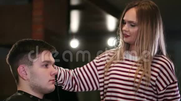 美容学校理发师用电动剃须刀剪雄性头发女性理发师给男性理发视频的预览图