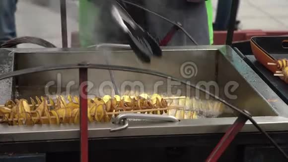 人在木棍上做深炸金螺旋薯脆脆的脆脆的把用热油煮熟的街头食品带走视频的预览图
