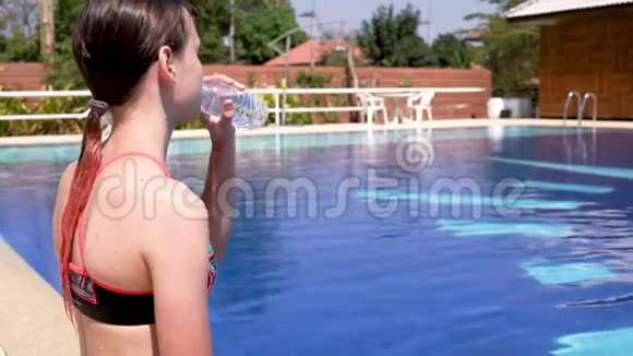 穿着泳装的可爱少女在泳池边喝水健康的生活方式观念视频视频的预览图