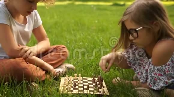 学校假期青少年智力游戏两个十几岁的女朋友在公园里下棋坐在草地上视频的预览图