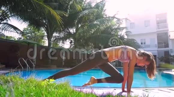 女士在泳池边做腿朝下的狗瑜伽姿势视频的预览图
