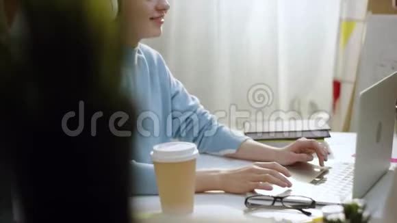 年轻快乐的女人听音乐用笔记本电脑工作视频的预览图