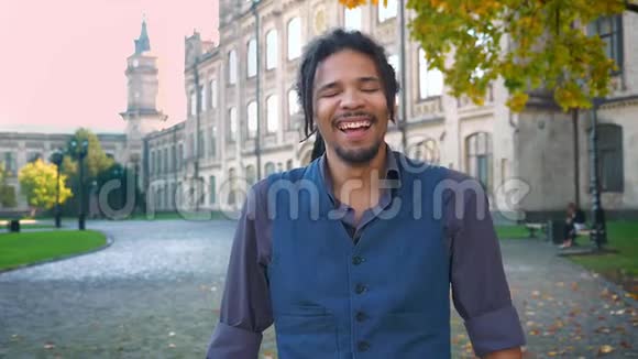 一张美国黑人青年的特写照片他戴着可怕的长发在大学背景下大笑视频的预览图