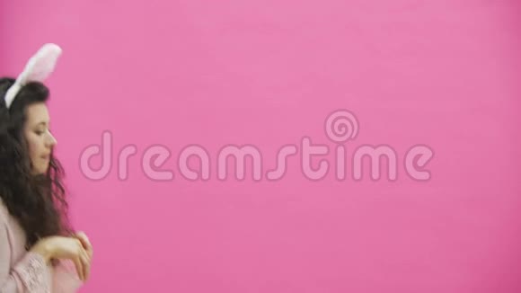 粉红色背景的年轻性感夫妇头上戴着黑黑的耳朵在此期间兔子跳跃重现了动作视频的预览图