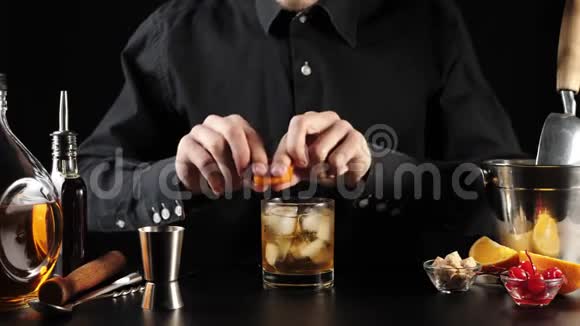 老式鸡尾酒调酒师用橙味的水滴在岩石玻璃的边缘以增强视频的预览图