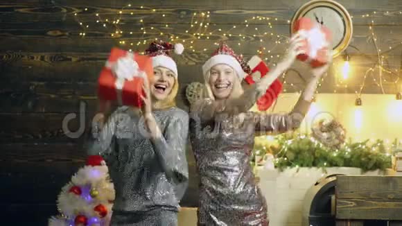 带着圣诞礼物跳舞的女孩圣诞背景上的疯狂女人带着礼品盒两个女人正在庆祝视频的预览图