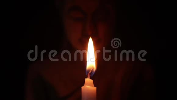 在黑暗中吹灭白色蜡烛在黑色背景上吹灭佛像视频的预览图