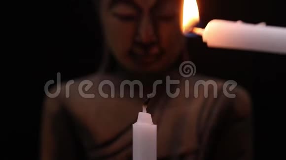 黑色背景的面佛像点燃蜡烛视频的预览图