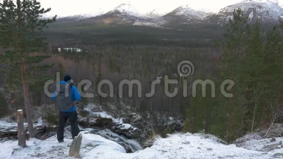 一个带背包的旅行者站在山上的高处他遇见美丽的风景欣赏美丽的风景视频的预览图