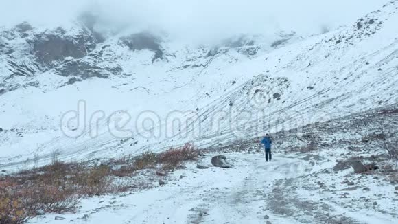 一个普通的中年男子在山区路线上旅行他一个人走在下雪的路上视频的预览图