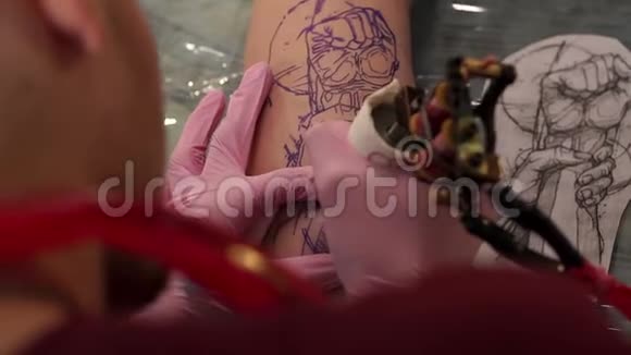一个戴着粉红色手套的男人的特写在一个年轻女孩的腿上纹身视频的预览图