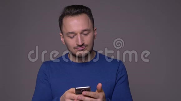 特写镜头年轻英俊的高加索男子在电话短信与背景隔离在灰色视频的预览图