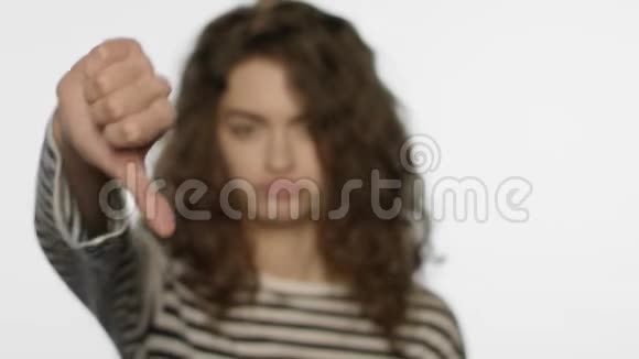 伤心的女孩在演播室里竖起大拇指不喜欢手势的女人视频的预览图
