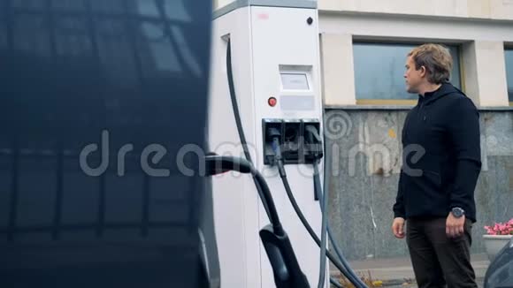 男人在一个车站和一台汽车充电机一起工作关门视频的预览图