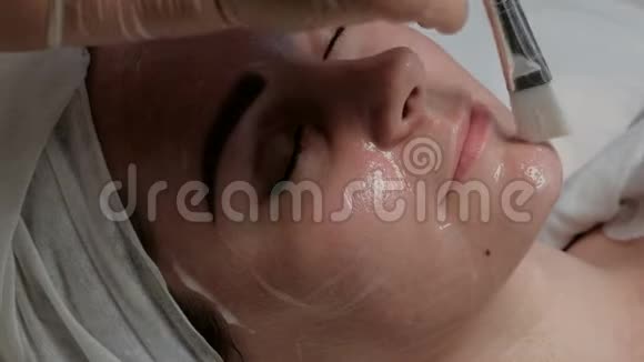 一个可爱的女孩在美容院做面部护理时微笑特写镜头专业的美容师在视频的预览图